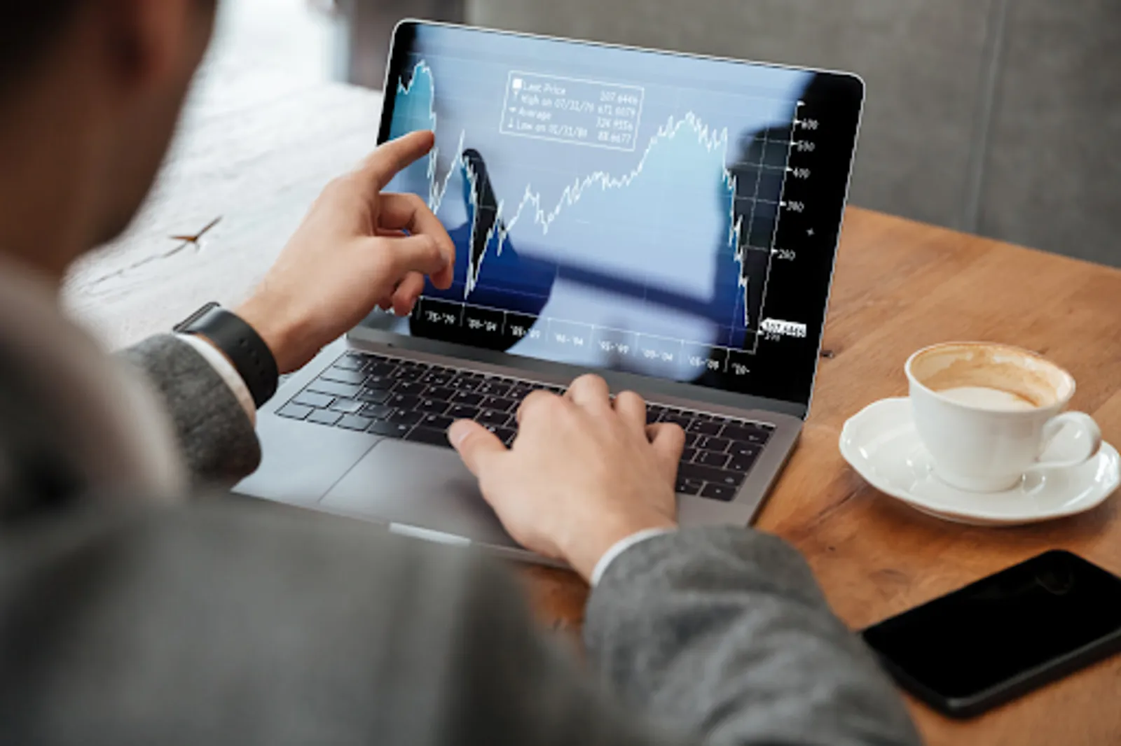 a man looking at trading chart on a laptop
